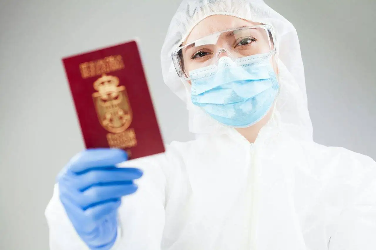 medical-healthcare-worker-in-full-personal-protective-equipment-holding-red-passport.jpg
